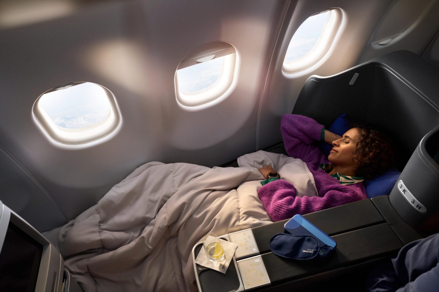 Intercontinental Business Class A woman lies on a seat in Business Class with a blanket