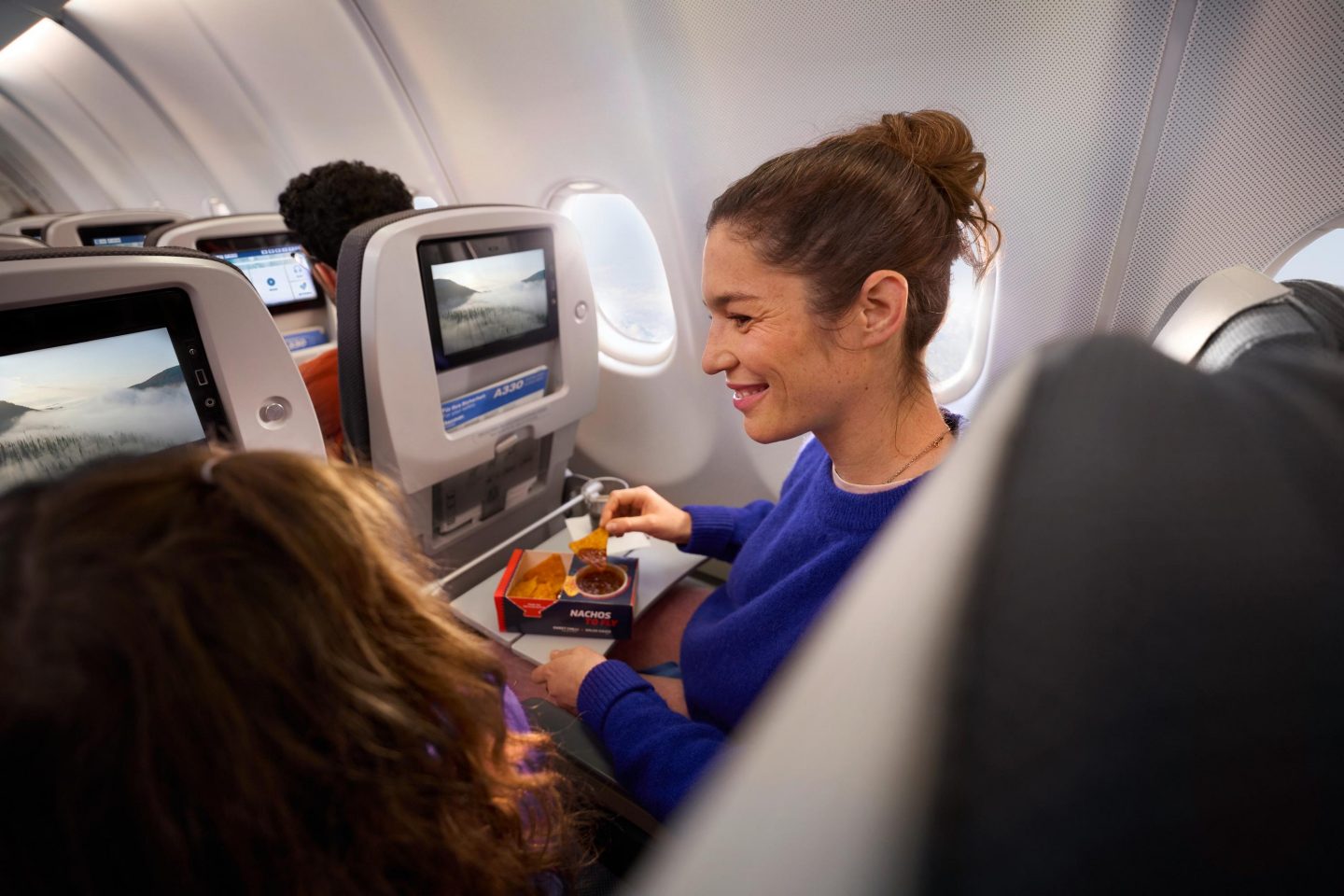 Economy Class Intercontinental A woman eats a snack from the Onboard Bar in Economy Class