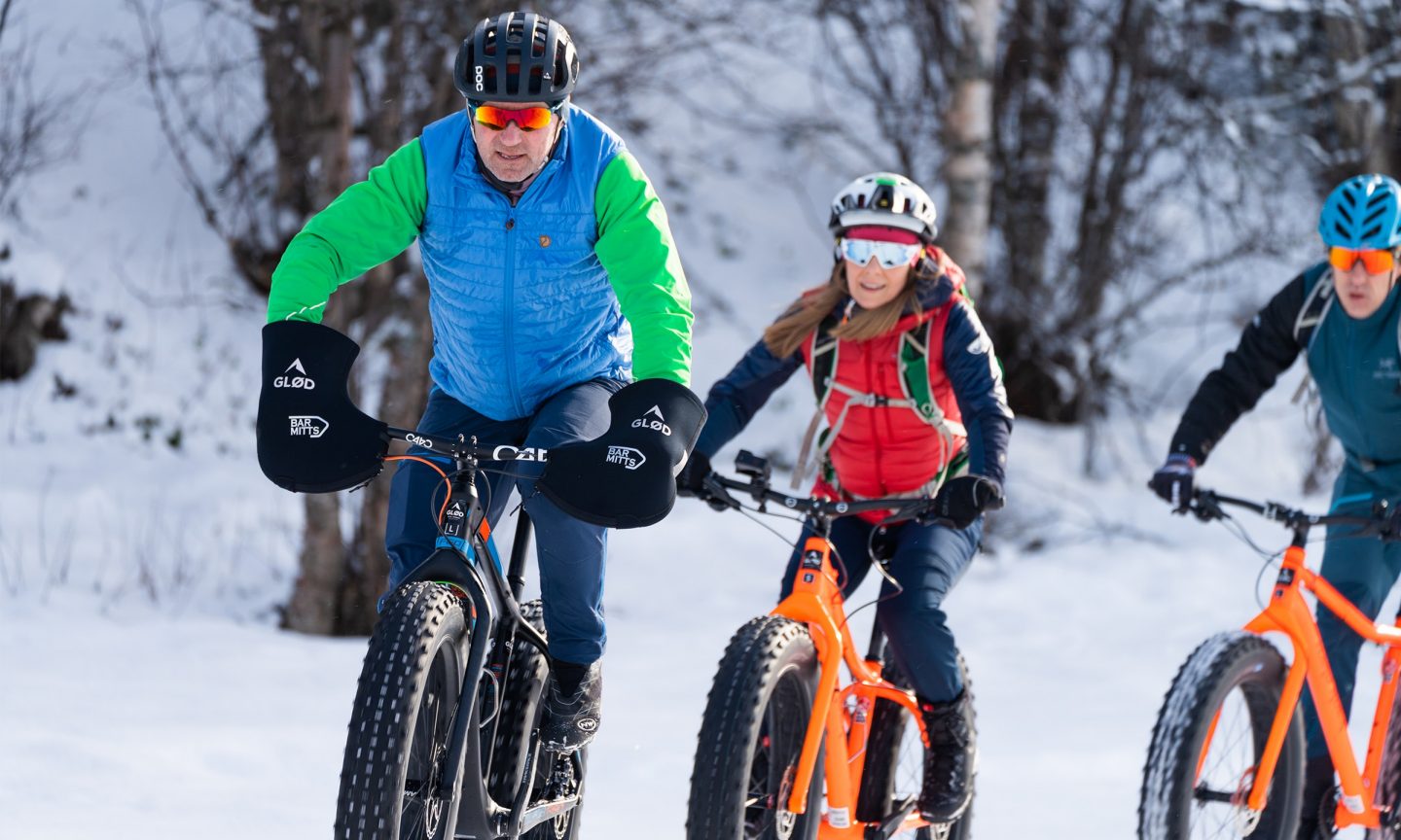 Drei Menschen fahren Fahrrad durch den Schnee