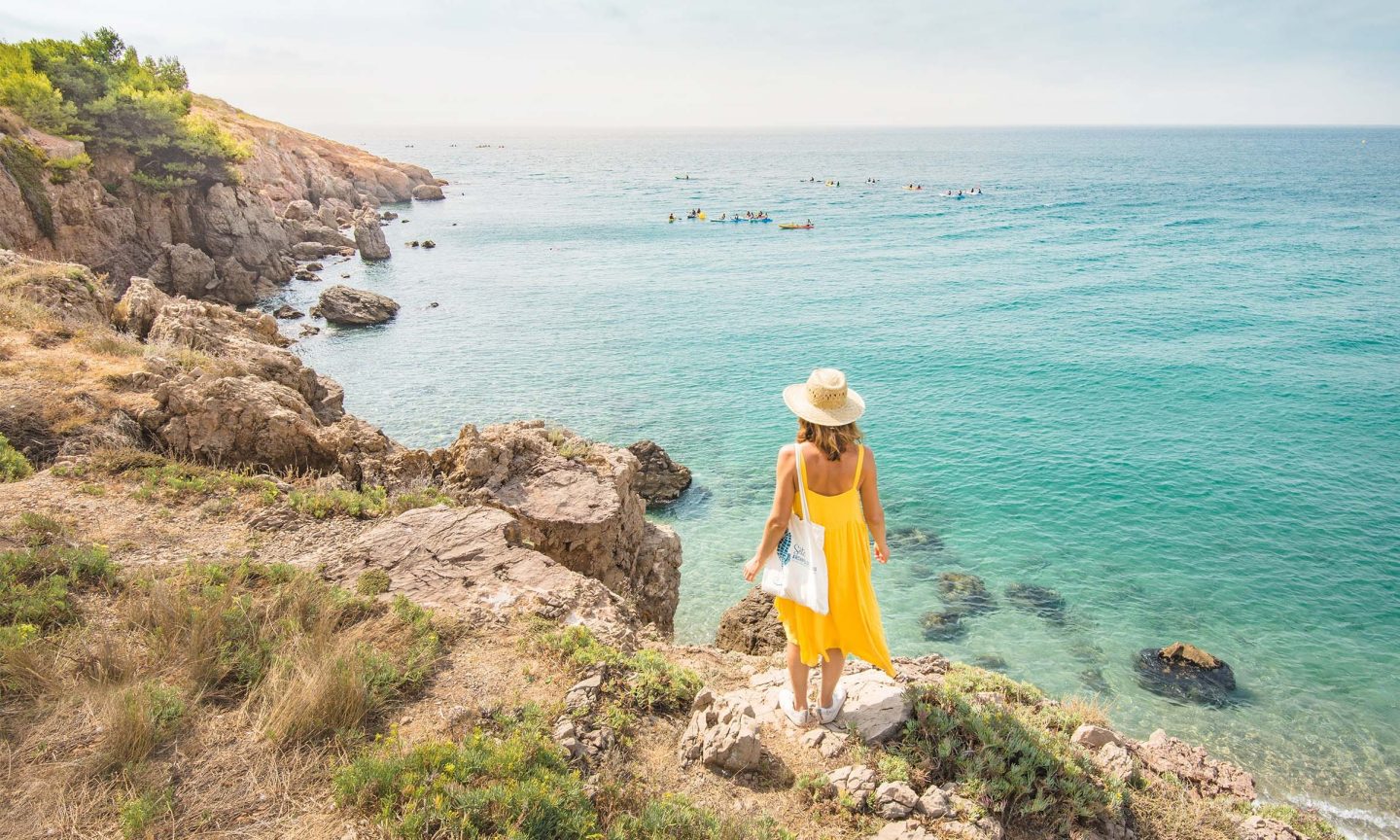 Eine Frau in einem gelben Kleid steht an der Küste in der Nähe von Montpellier