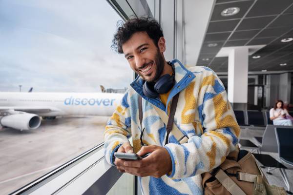 Eine Person steht am Gate und hat ein Handy in der Hand