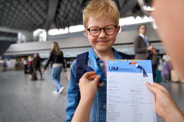 Frau legt alleinreisendem Kind ein Formular um