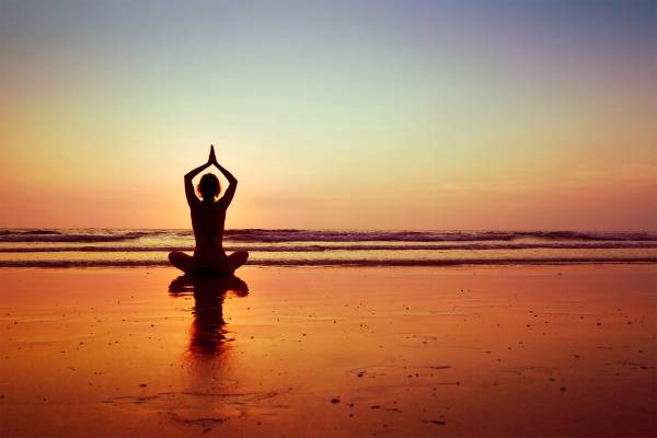 Frau macht Yoga am Strand von Ibiza